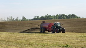 En traktor gödslar i jordbrukslandskap